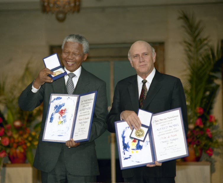 Two men pose with their Noble Peace Prize medals and diplomas.