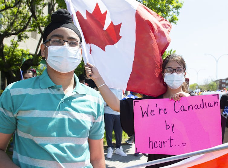 People wearing masks hold signs at a rally