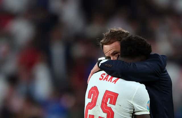 England coach Gareth Southgate embraces player Bukayo Saka after he missed a key penalty kick