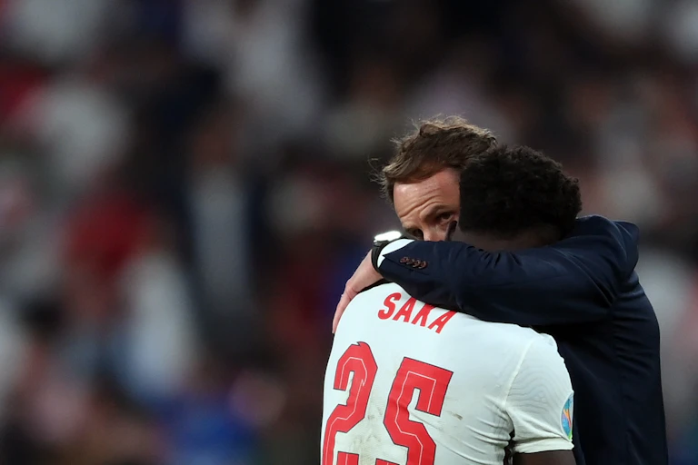 England coach Gareth Southgate embraces player Bukayo Saka after he missed a key penalty kick