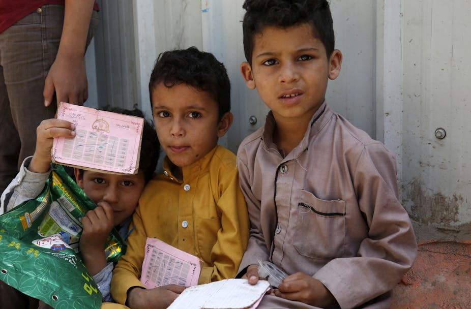 Three Yemeni children shown waiting for food rations.
