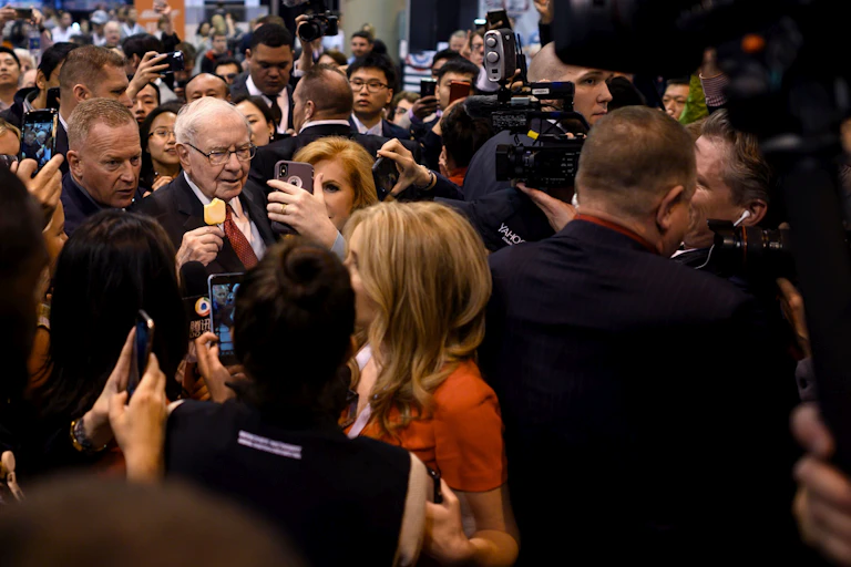 Warren Buffett, thronged by members of the media