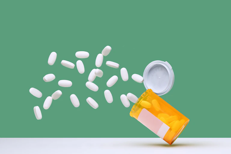 White pills spilling out of falling prescription bottle