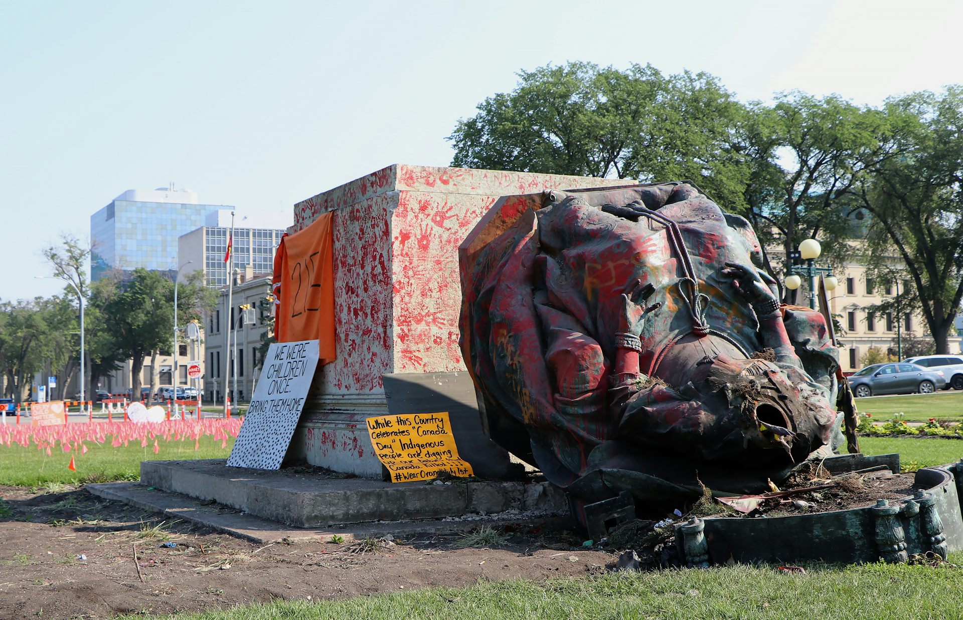 Headless statue lying on the ground covered in protest signs and red paint