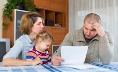 Couple with young child looks despondent and ponders paperwork.