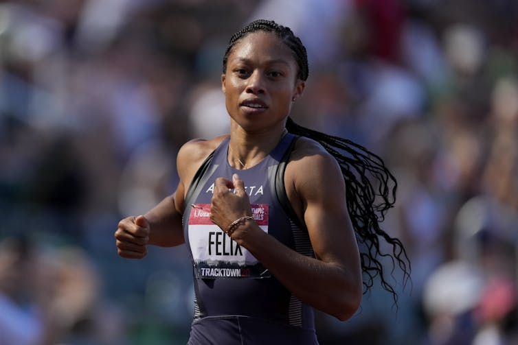 Woman running wearing a tank top with FELIX across the front