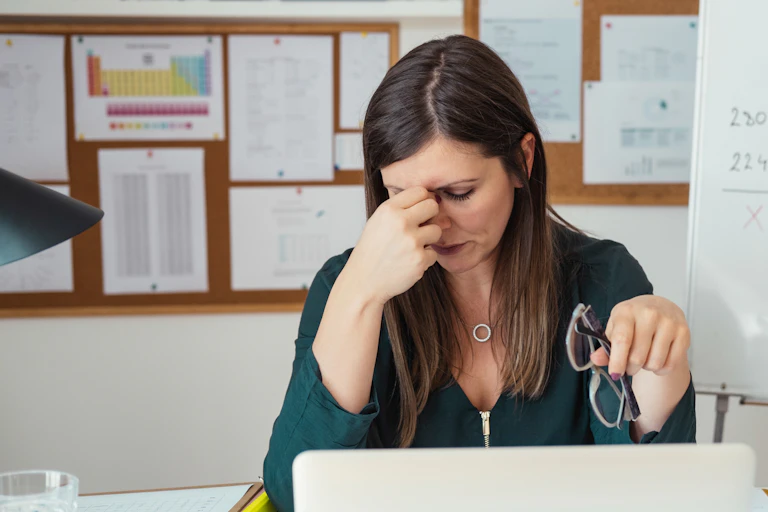 Women with a headache sitting in front of laptop