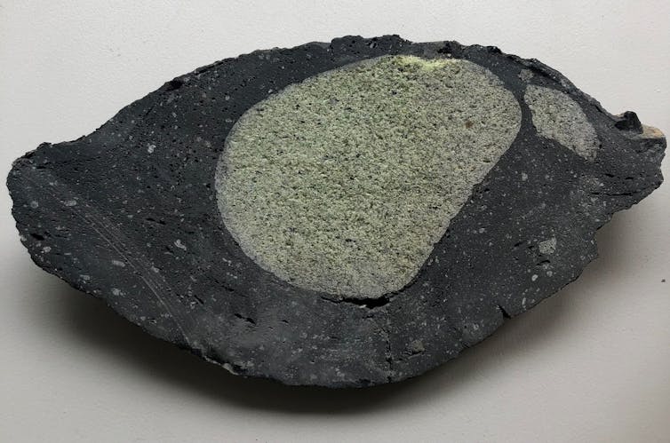 Green rock blob encased in black rock