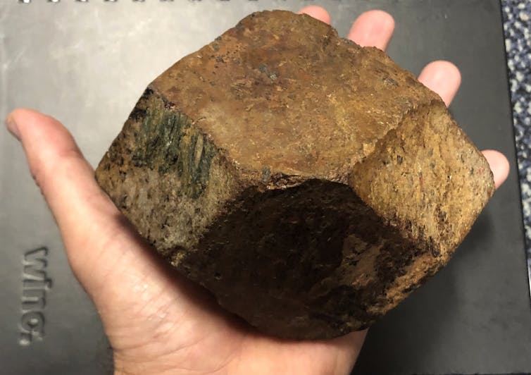 A geologist holding a rock with various colours