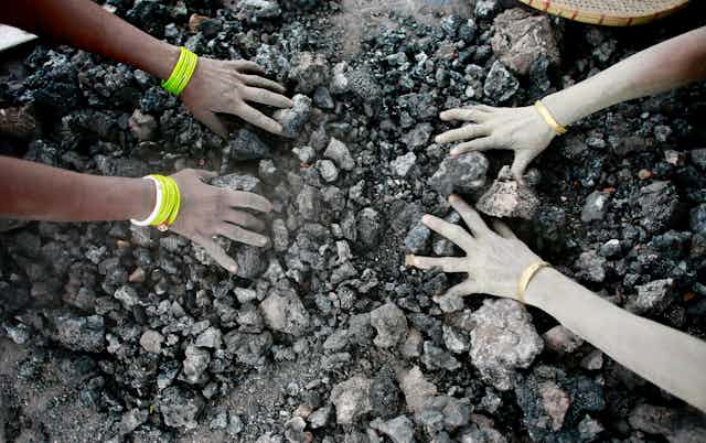 hands touching coal pieces