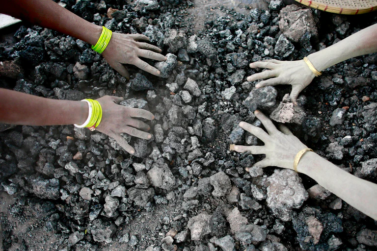 hands touching coal pieces