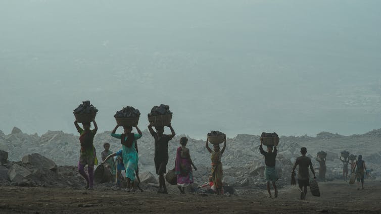 people carry baskets filled with coal
