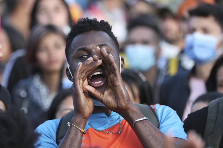 a young man yells with his hands cupped around his mouth
