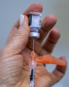 A hand preparing a dose of COVID-19 vaccine