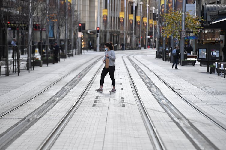 Woman walks across an empty Sydney mall.