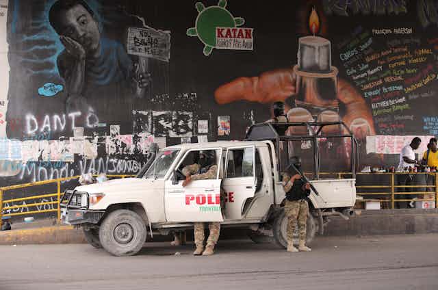 Police officers deploying in front of a political mural in the capital of Haiti, Port-au-Prince, July 2021.