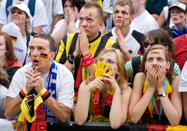 German football fans put their hands over their faces