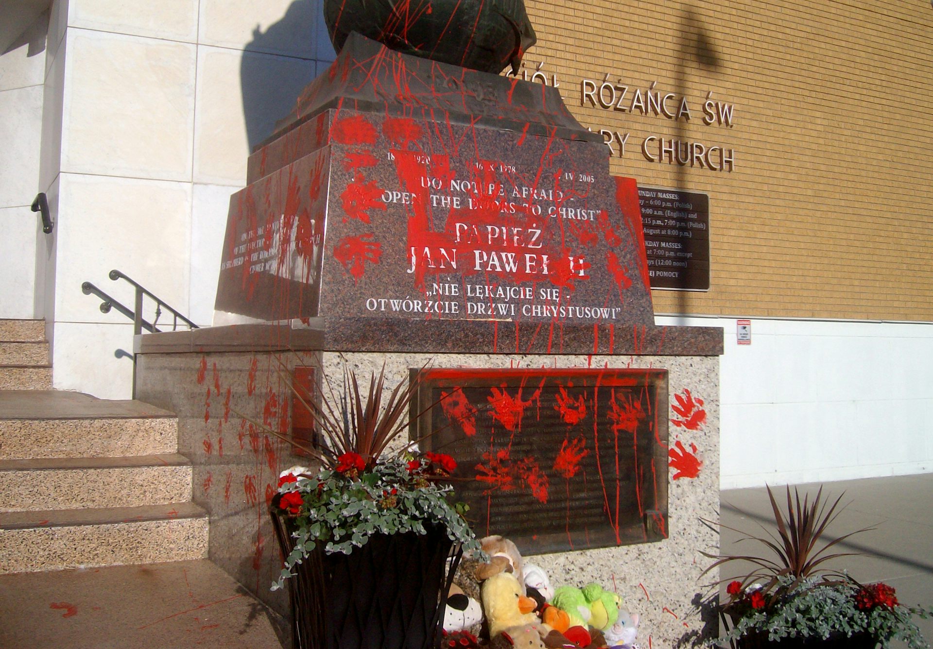 A statue of the late Pope John Paul II, standing at the Holy Rosary Catholic Church, has been vandalized with red paint splatter and handprints