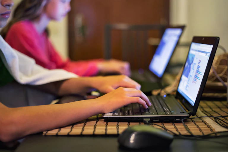 Students type on their laptops.