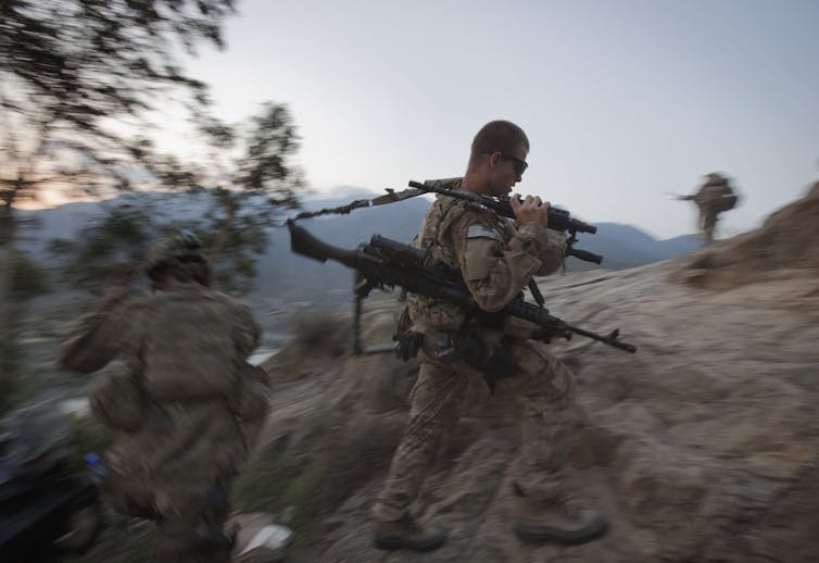 A soldier hikes up to begin an overwatch shift on a hilltop observation post in Afghanistan's mountainous Kunar province.