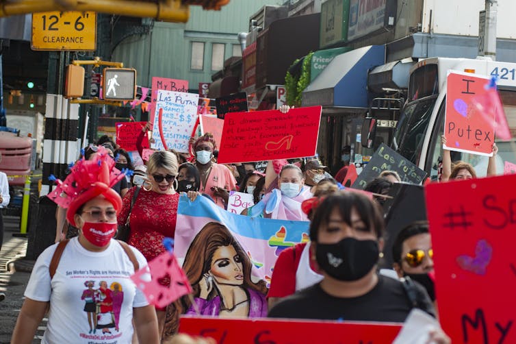 Protesta callejera de personas con máscaras faciales y carteles que exigen derechos