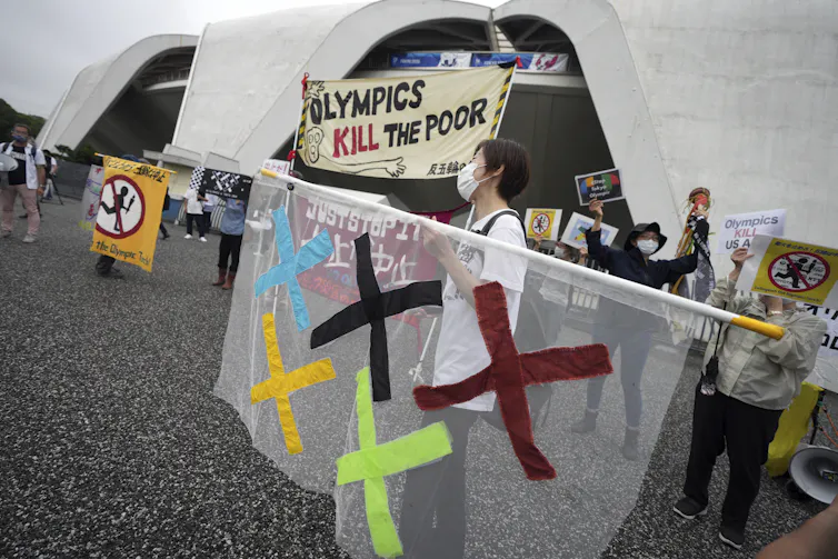 Protester holding a sign that says 'Olympics kill the poor.'