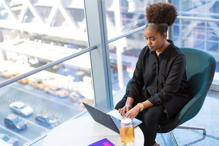 Professional woman of African decent types on laptop.