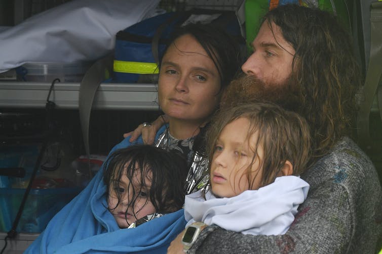 man, woman and two children in blankets