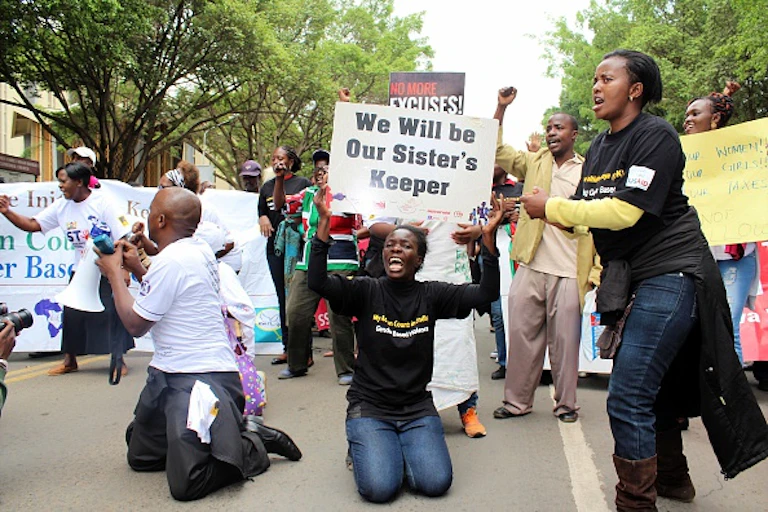 People kneeling and standing on the streets with placards protesting sexual harassments.