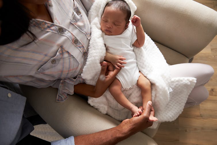Woman holding newborn baby in chair.
