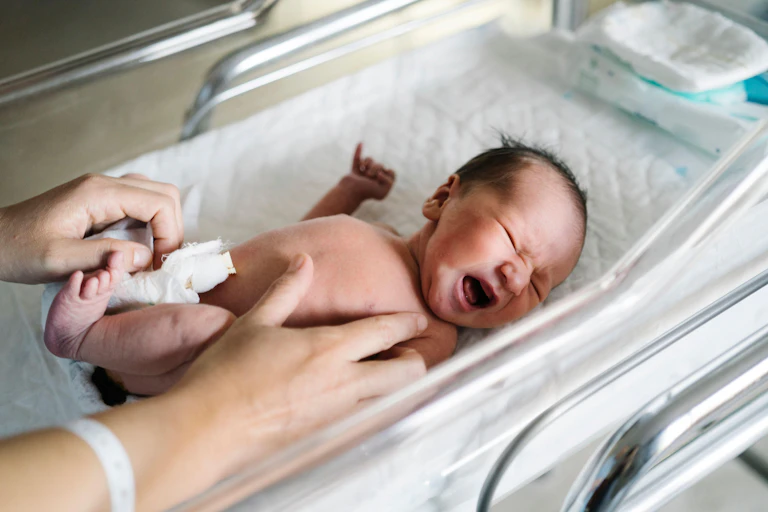 Newborn baby having nappy changed.