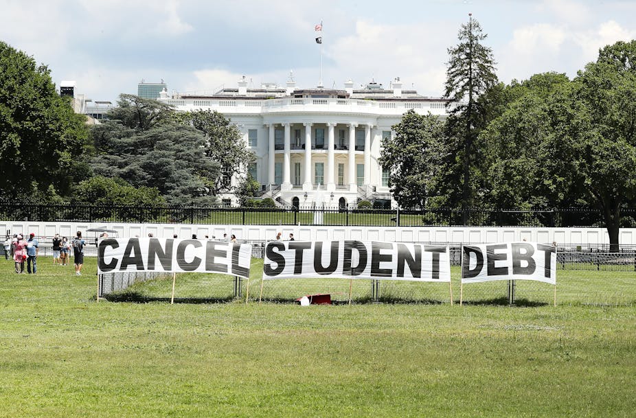 A sign that reads 'cancel student debt' is placed in from of the White House lawn.