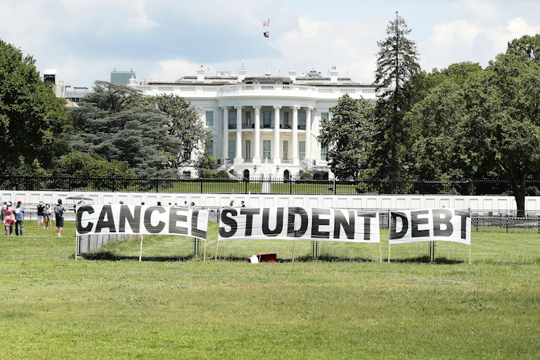 A sign that reads 'cancel student debt' is placed in from of the White House lawn.