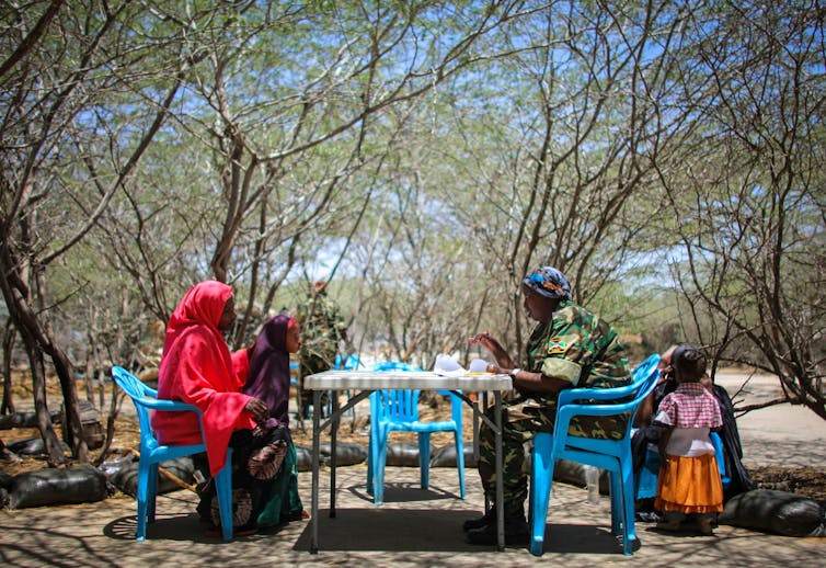 A group of people dressed colourfully talk over a table