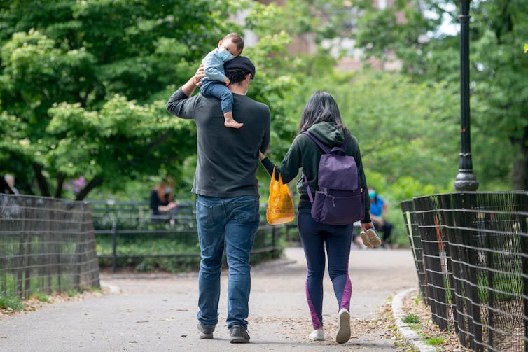 A man, woman and baby walk through a park together