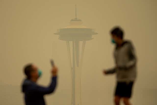 A man and boy outside the Seattle Space Needle shrouded in smoke
