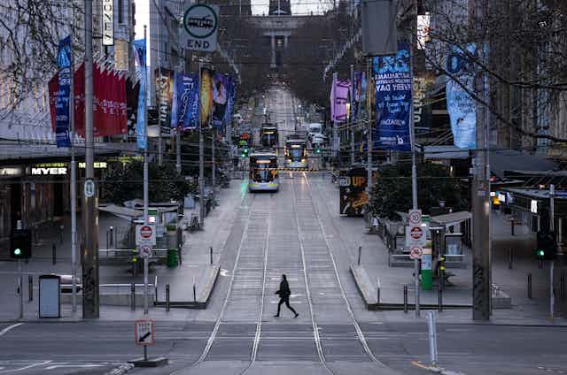 Empty streets of Melbourne CBD with one pedestrian and trams in the distance