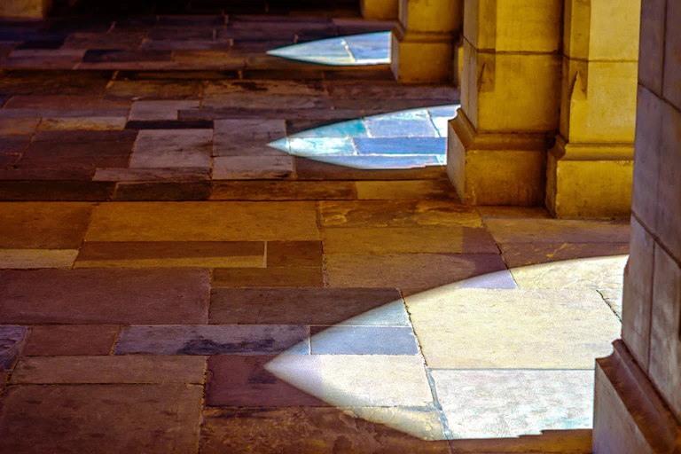 Sunlight falls onto slate tiles through stone archways at the University of Melbourne in Australia