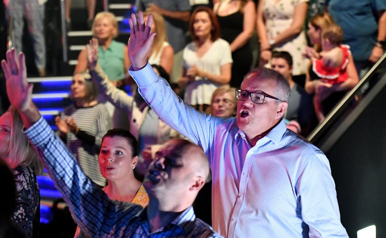 Man raises arm as he sings during a church service