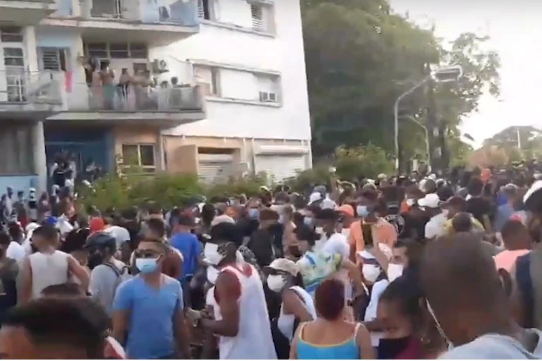 Large crowd outside apartment block, most wearing COVID masks.