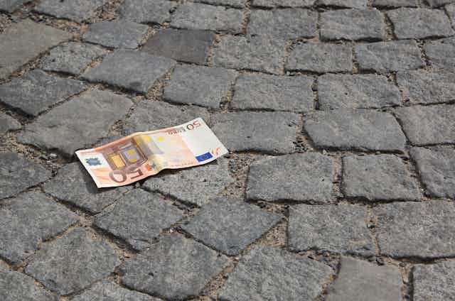 Billete de 50 euros en un suelo adoquinado.
