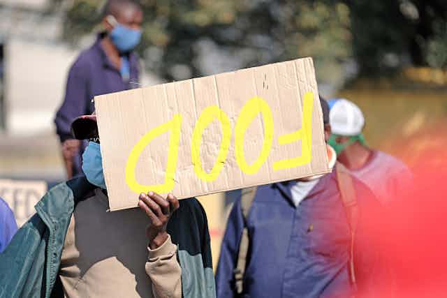 Person holding up a placard that reads "Food"