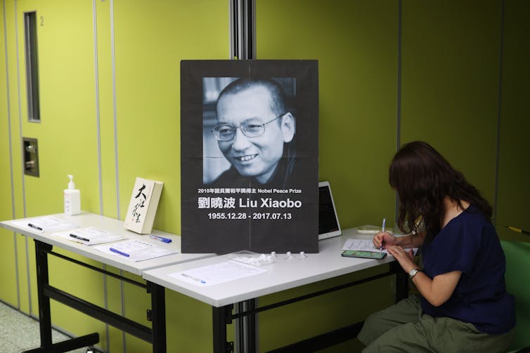 A woman writes in a book of condolences in front of a portrait of deceased Chinese democracy activist Liu Xiaobo, Hong Kong, 2020.
