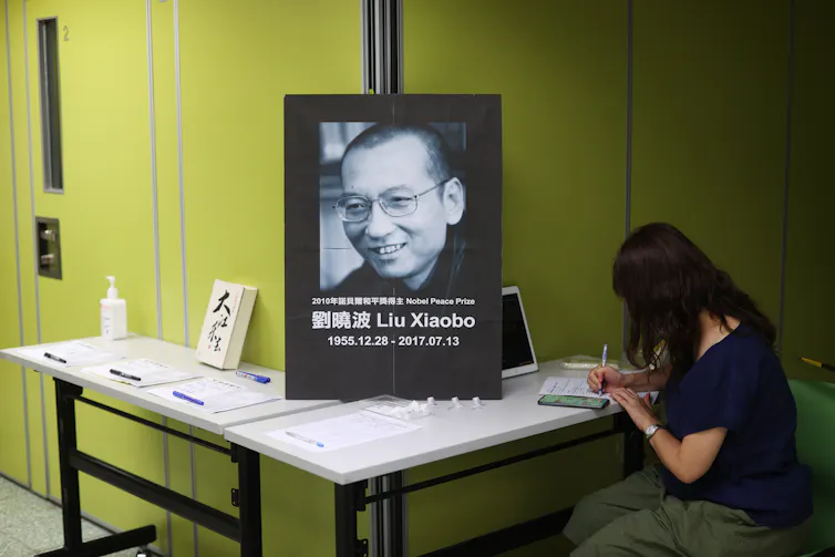 A woman writes in a book of condolences in front of a portrait of deceased Chinese democracy activist Liu Xiaobo, Hong Kong, 2020.