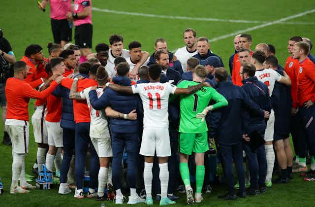 The whole England teams huddles.