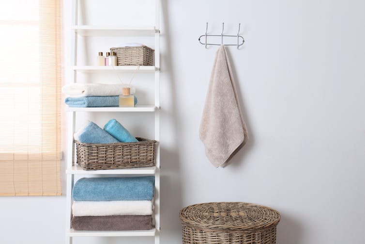 A bathroom hand towel hanging next to a shelving unit.