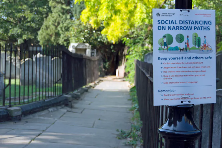 A sign outlining social distancing rules on a lamppost.