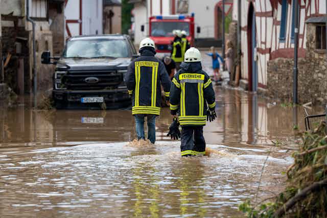 Firefighters walk through flooded village