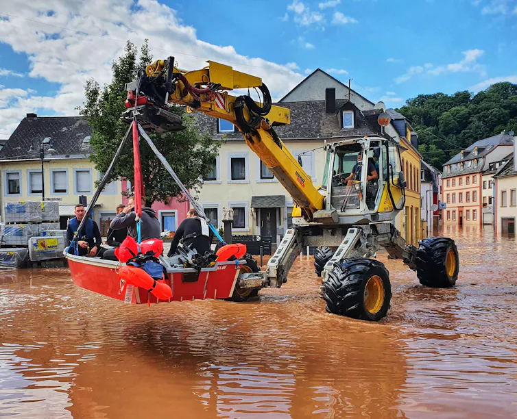 A digger left up a boat containing people in a flooded town