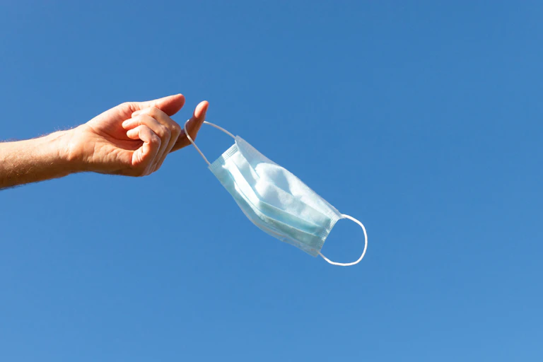 Person dangling a mask on the end of their index finger